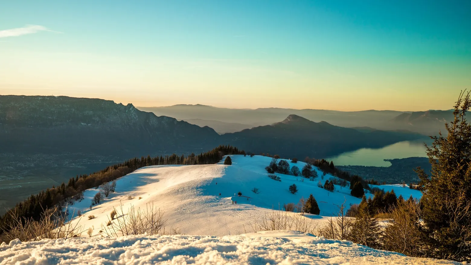 Le plateau du Revard sous la neige au coucher du soleil, avec le lac du Bourget et le massif des Bauges à l’horizon